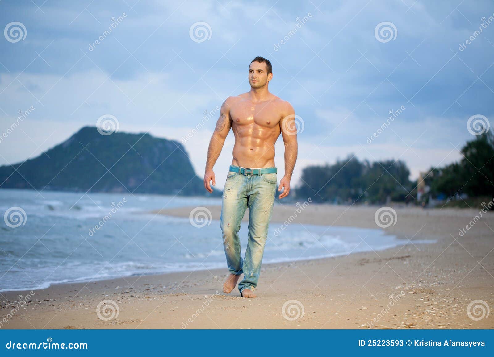 muscular male walking along a beach