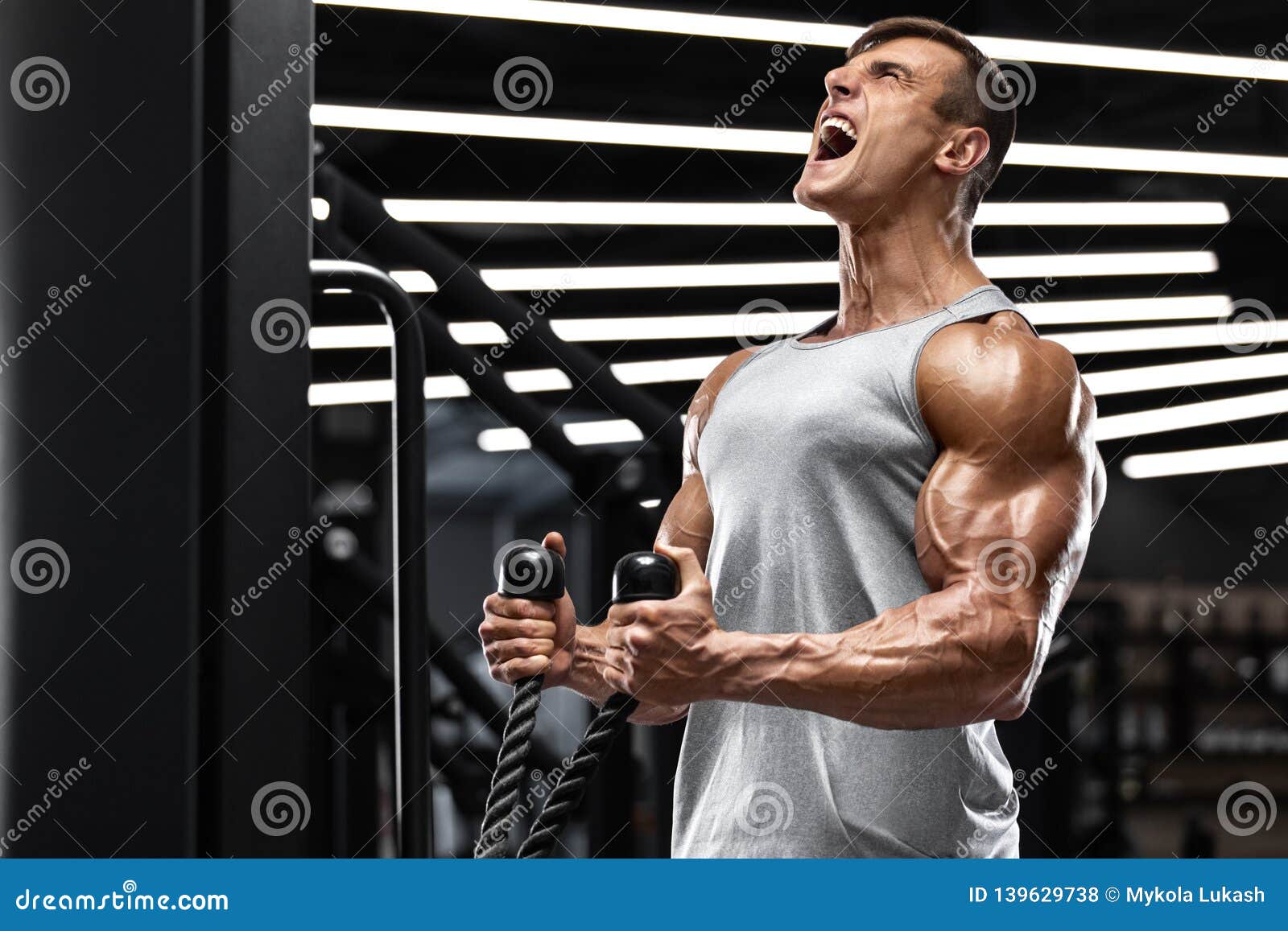 Muscular Man Working Out In Gym Doing Exercises For Biceps 