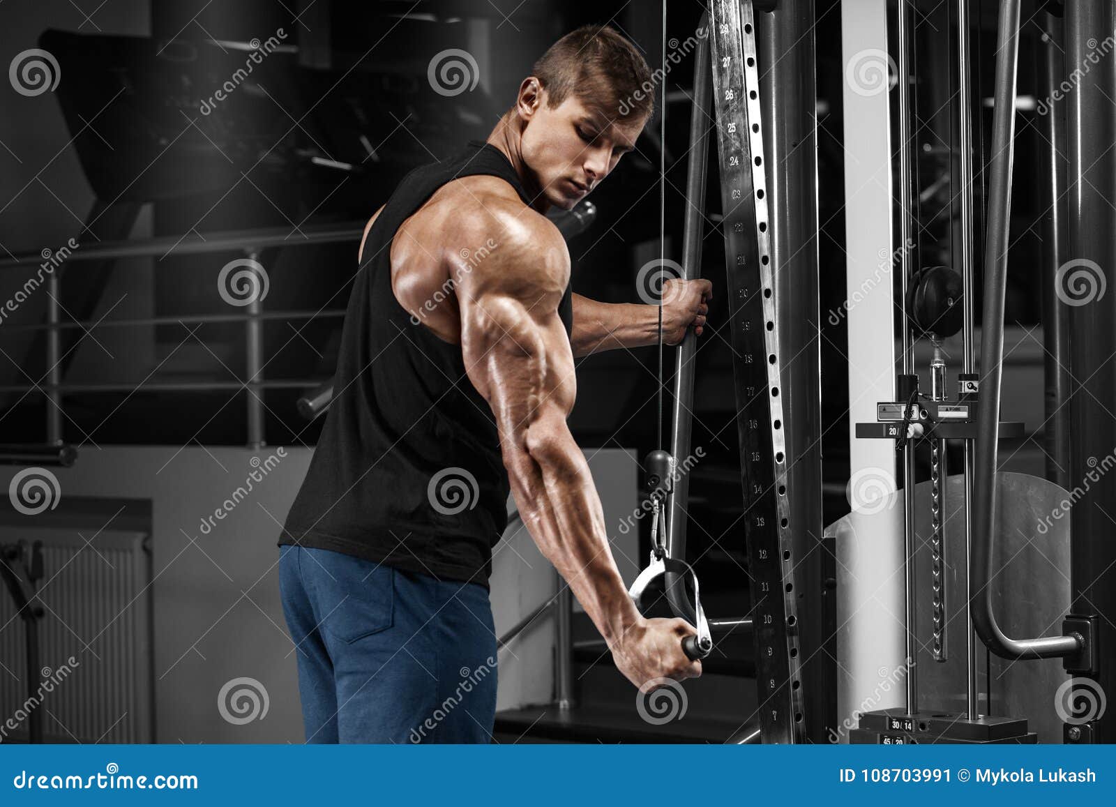 muscular man working out in gym doing exercises at triceps, strong male