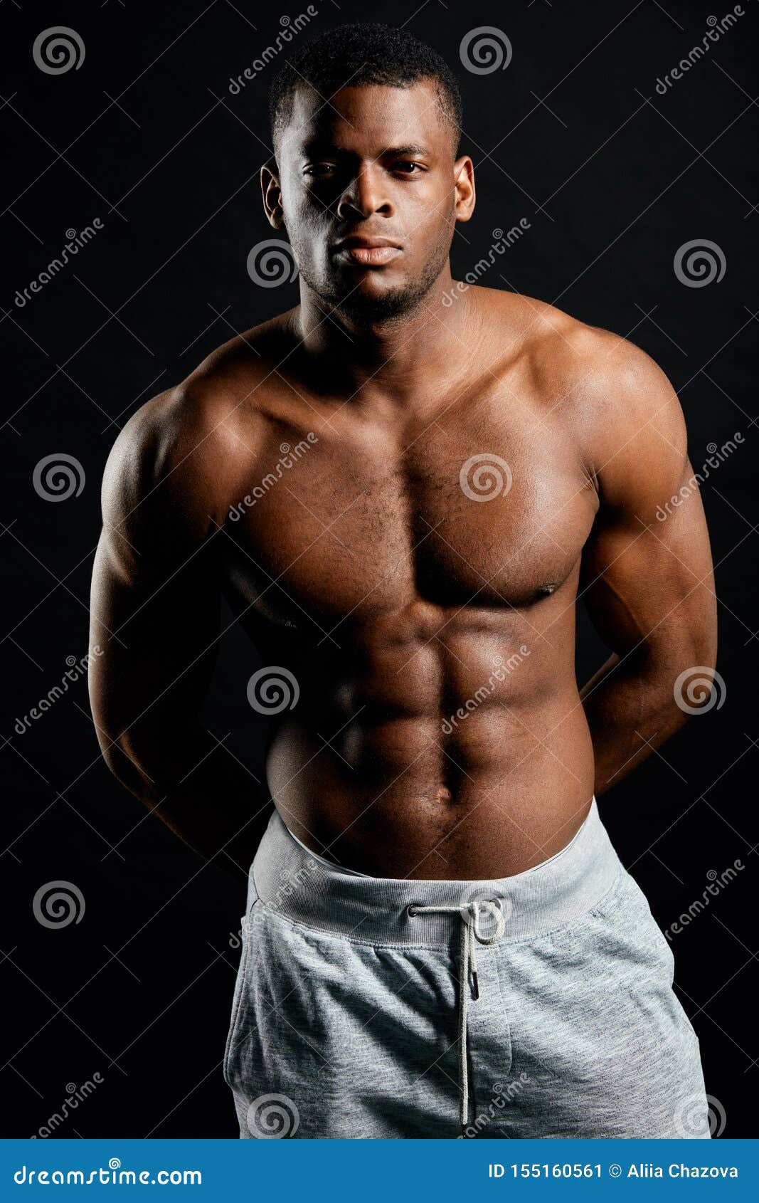 Muscular Serious Bodybuilder with Hands on His Back Looking at the