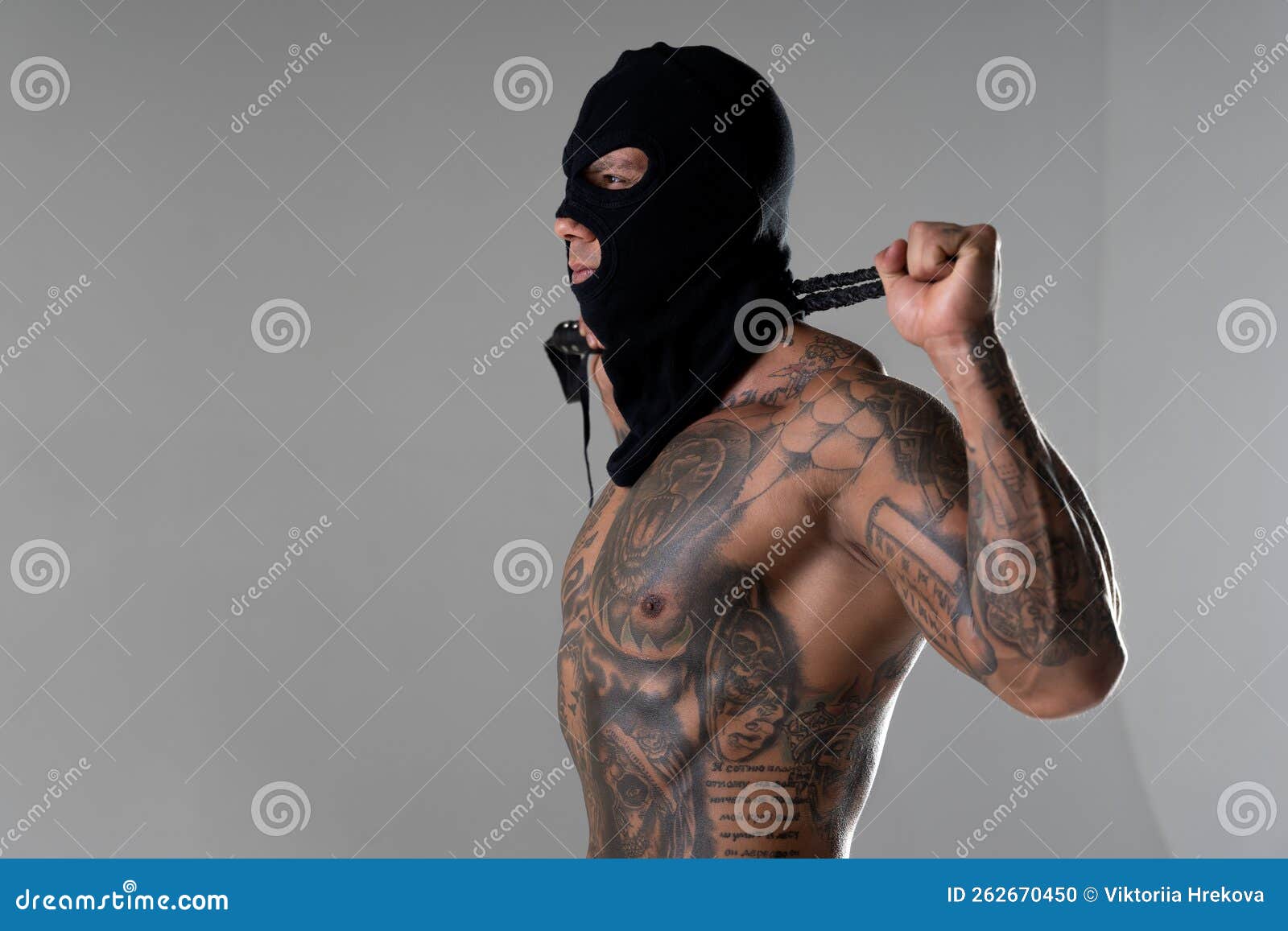 Muscular shirtless young man with whip in a mask.Brutal handsome man with  tattooed body. Men tattoo casual fashion. Portrait of handsome male model.  Muscular athletic sexy male with naked torso. Photos