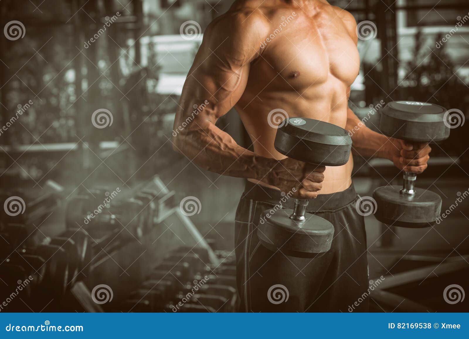 muscular young man lifting weights at fitness center.