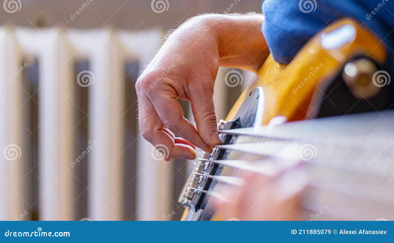 the musician plays a five-string bass guitar at home