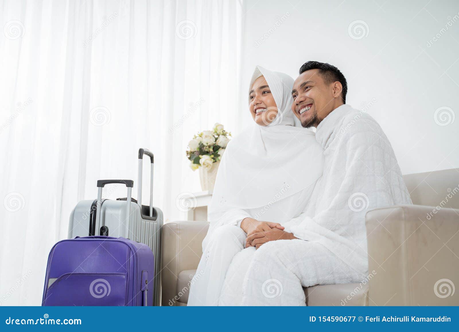 muslim couple sit wearing white traditional clothes before umrah