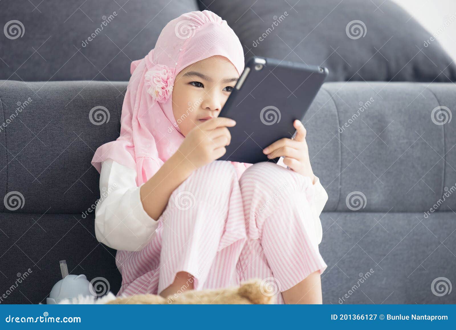 muslim girl is watch vdo online via internet on tablet at living room in morning