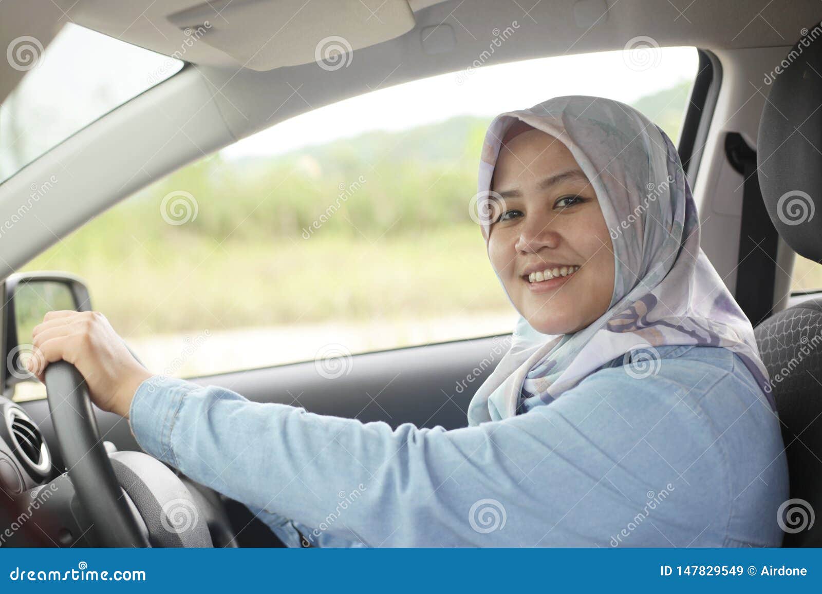 muslim lady driving her car and smiling