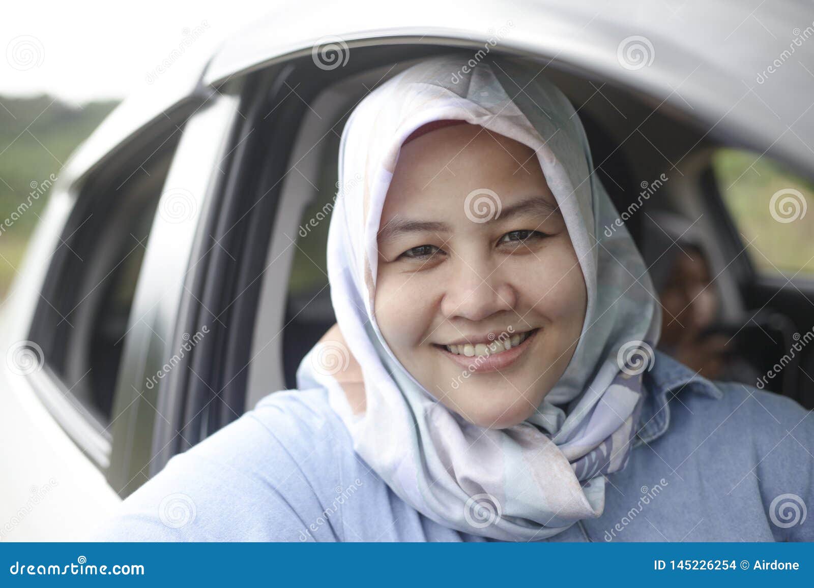 muslim lady driving her car and smiling