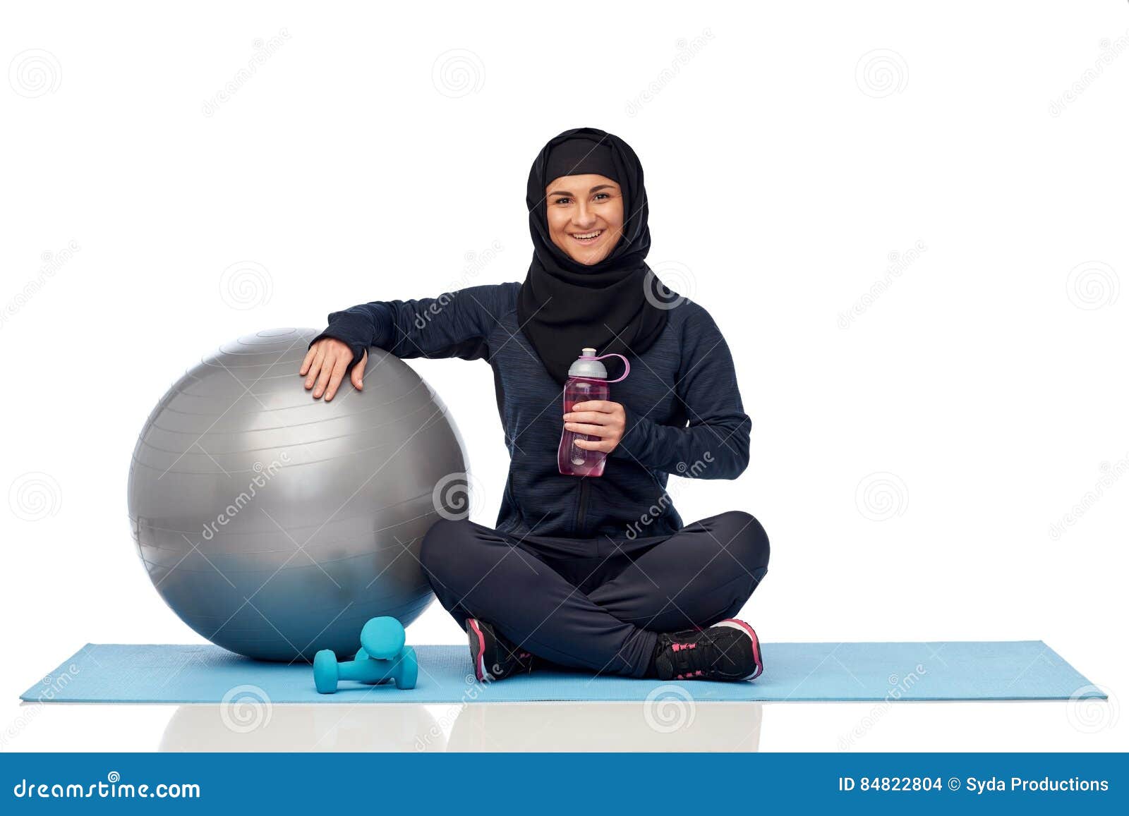 muslim woman in hijab with fitness ball and bottle