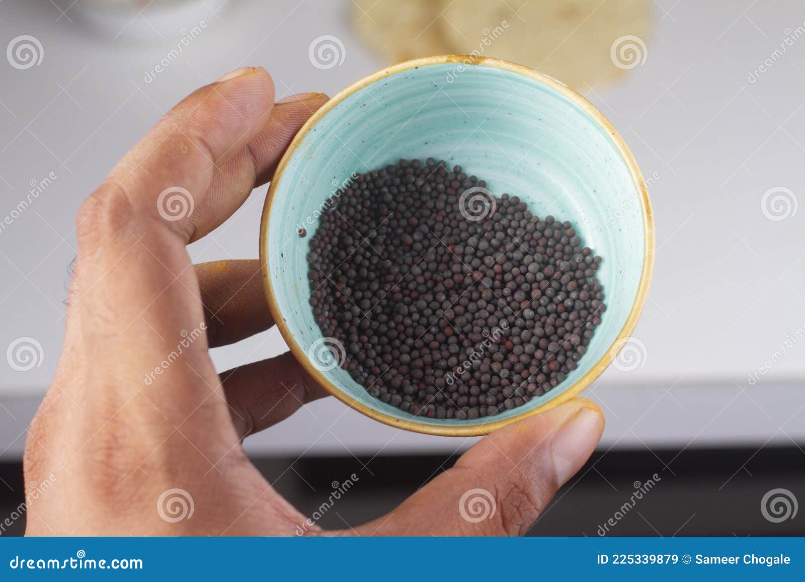 mustard seeds bowl in hand  on light background