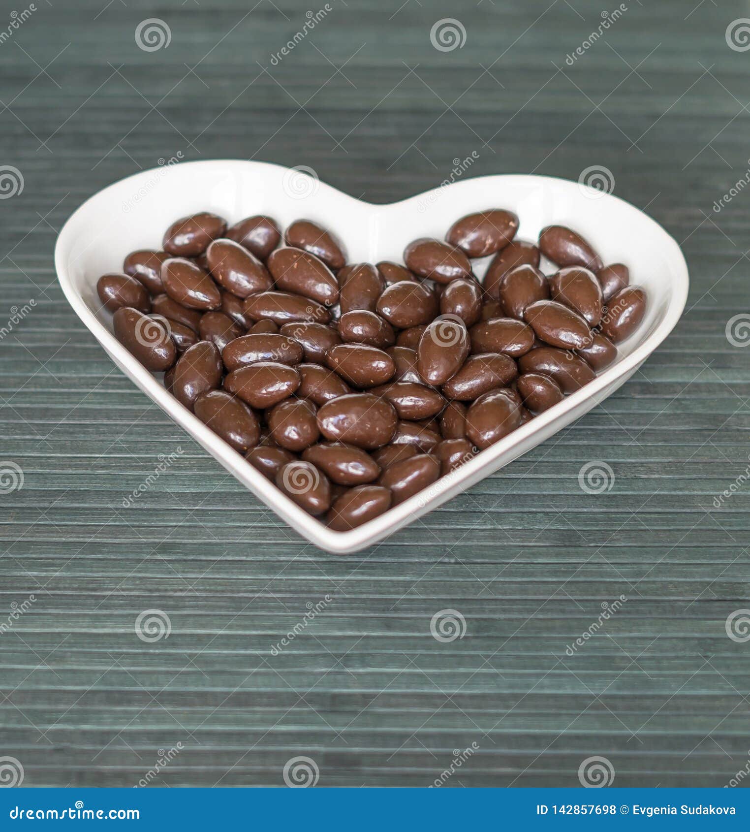 Nuts arranged in heart shape on background. Food image close up candy, chocolate milk, extra dark almond nuts. Love Texture.