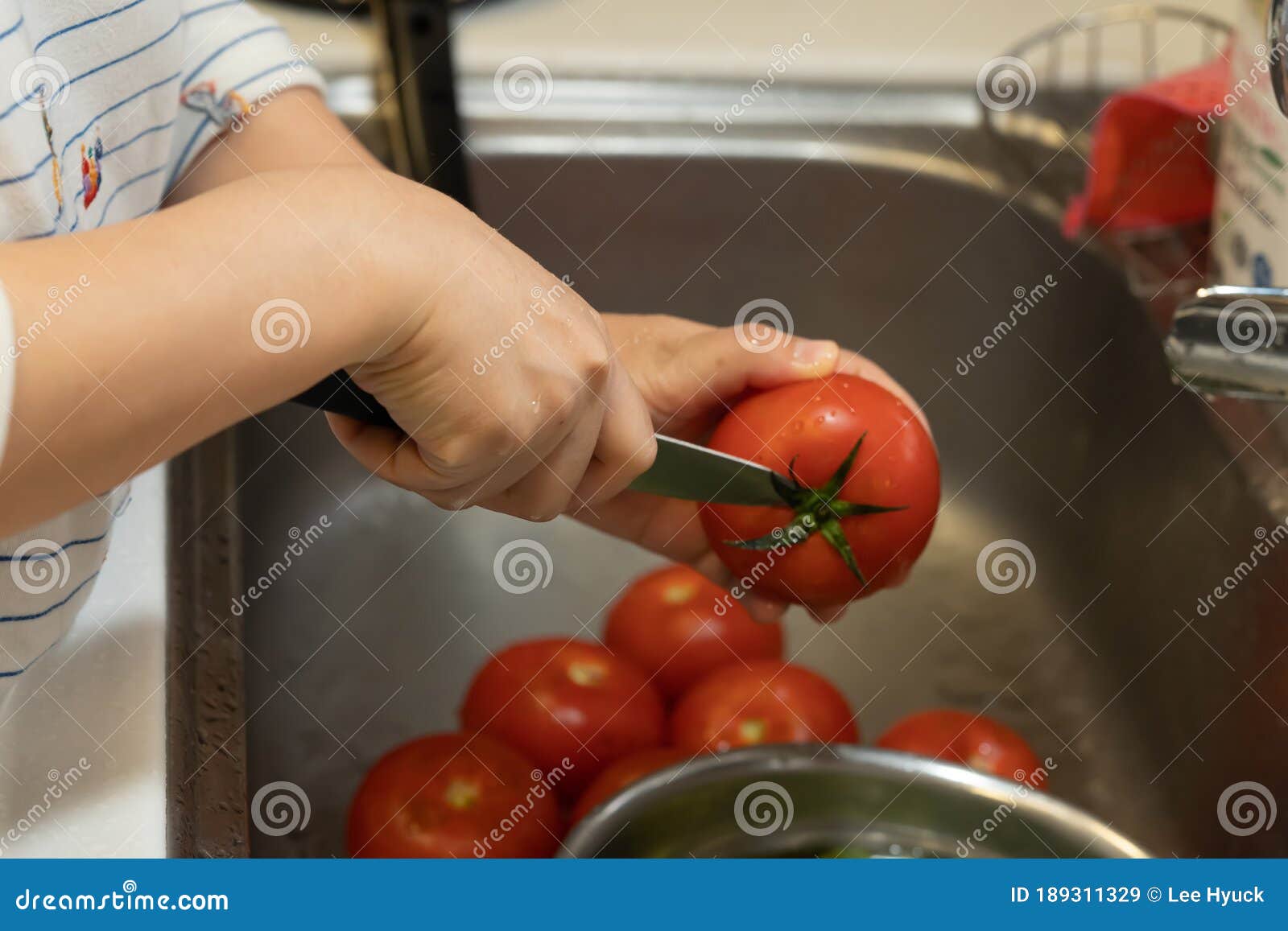 the cook is removing the top of the tomato with a knife