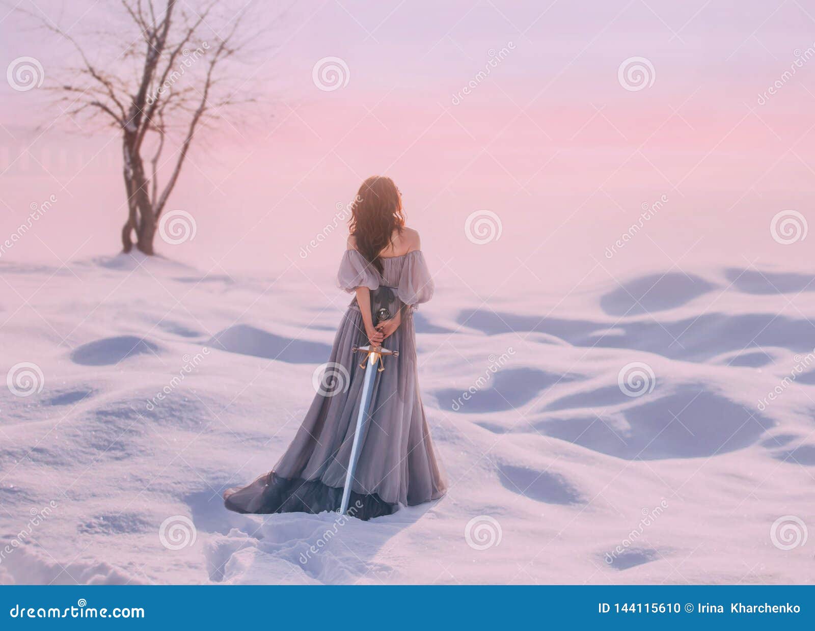mysterious lady from middle ages with dark hair in gentle gray blue dress in snowy desert with open back and shoulders