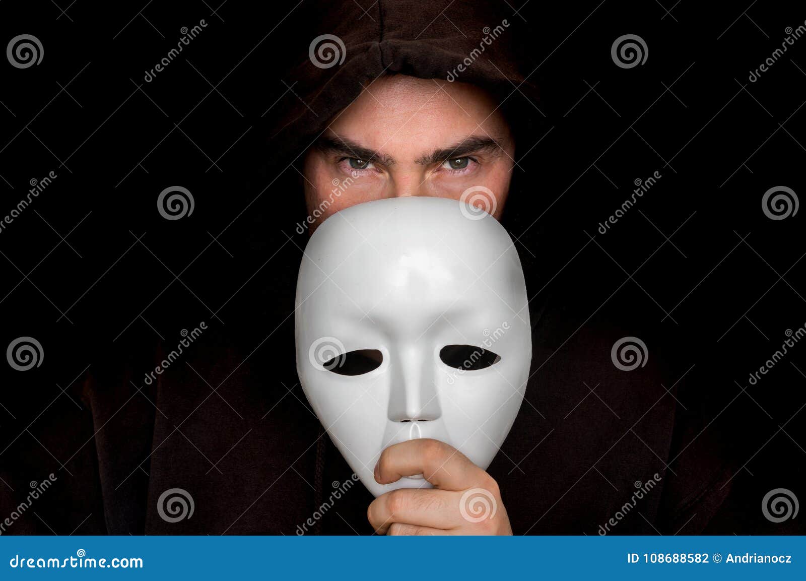 mysterious man in black hiding his face behind white mask