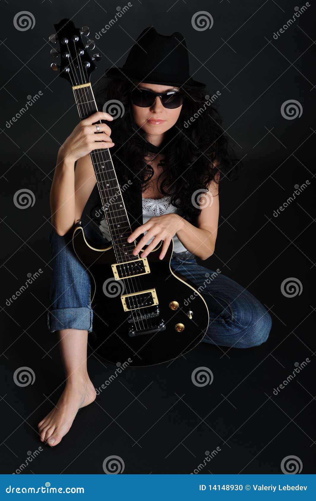Mädchen-Musiker. Weiblicher Musiker sitzt auf dem Fußboden, mit einer Gitarre in der Hand