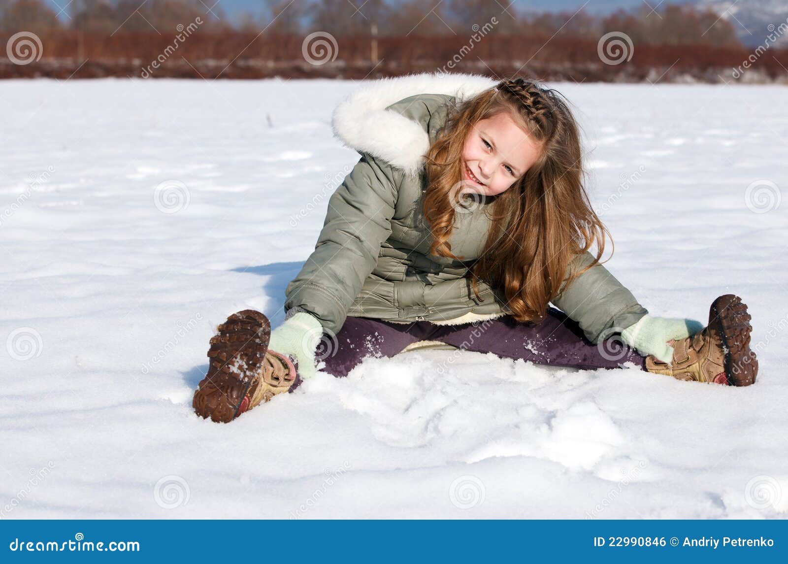 Mädchen sitzen sich im Schnee hin. Glückliches Kind sitzen sich im Schnee hin