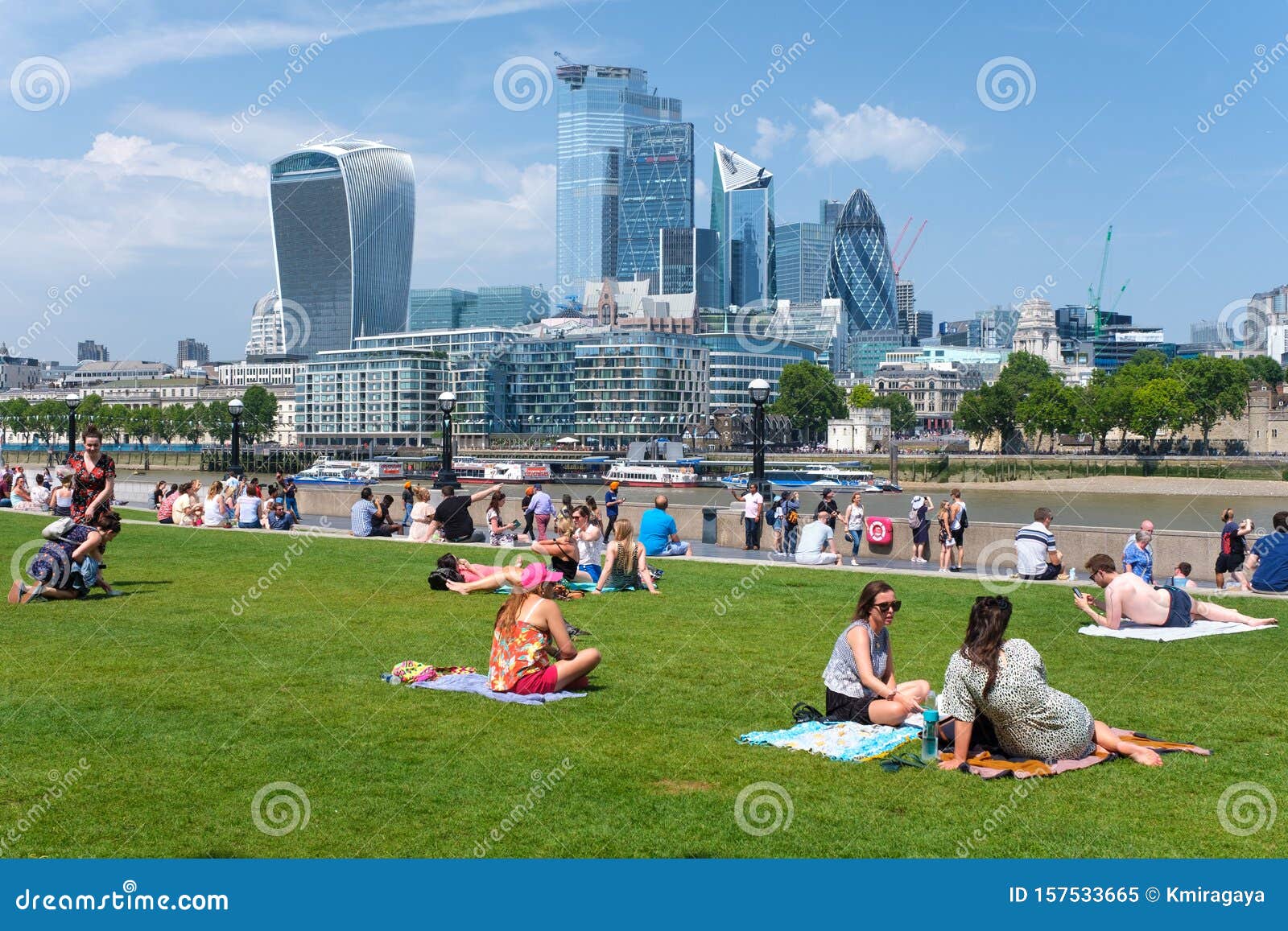 LONDON, UK - JULI 25 JULI 2019 : Människor som njuter av sommaren nära Tower Bridge i London med tanke på staden i bakgrunden, attraktionen, vacker, blå, brittisk, brittisk, brittisk, byggnad, dag, destination, England, England, Europa, Engelska, europeisk, flicka, gräs, stor, stor, semester, mark, fritid, man, modern, park, människa, slappna av, flod, flod, sittande, himmel, skyskare, southbank, southbank, vårs, sol, sol, sol, sol, sol, sol , solig, tames, turism, turism, resor, förenade, kungarike, semester, vattenfront, väder, kvinna, londonuk, 252019