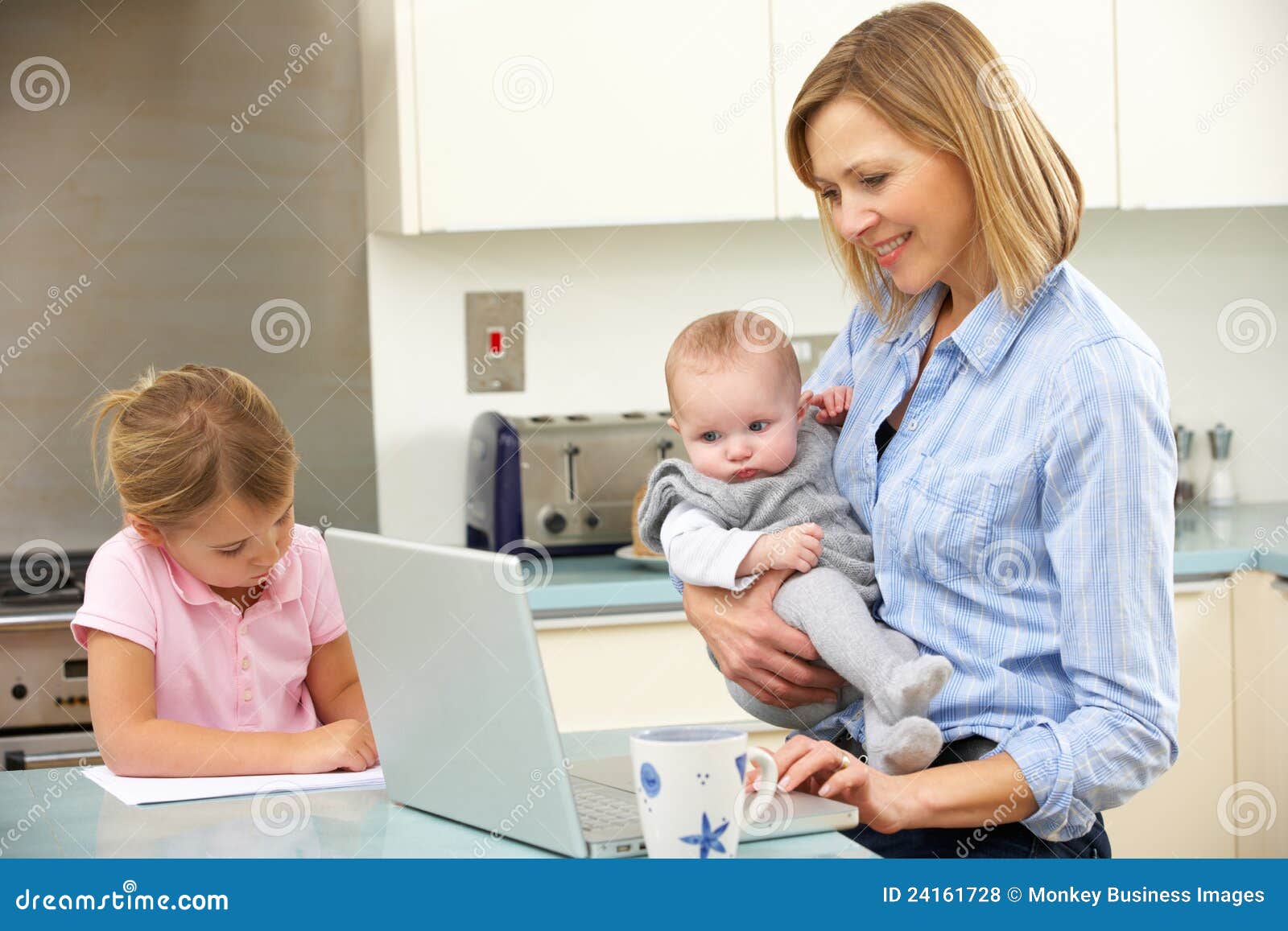 Mère avec des enfants à l'aide de l'ordinateur portatif dans la cuisine domestique