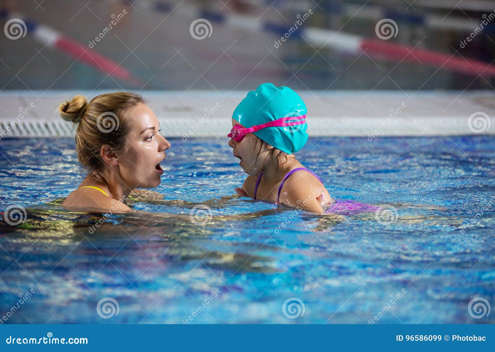 Mère ou instructeur enseignant la petite fille à retenir le souffle avant la plongée dans la piscine
