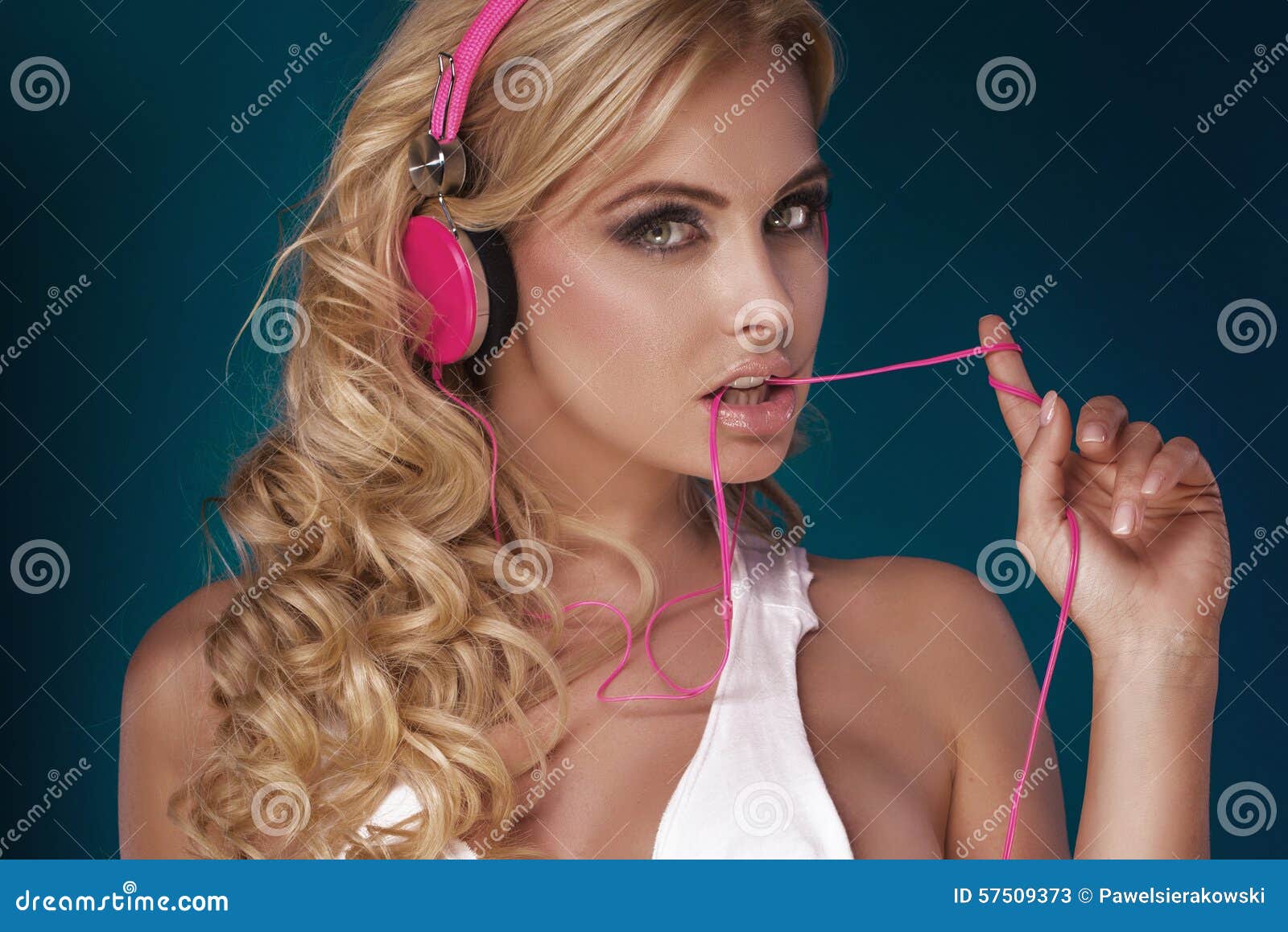 Música que escucha de la muchacha rubia. Retrato de la música que escucha de la mujer rubia atractiva por los auriculares rosados Tiro del estudio