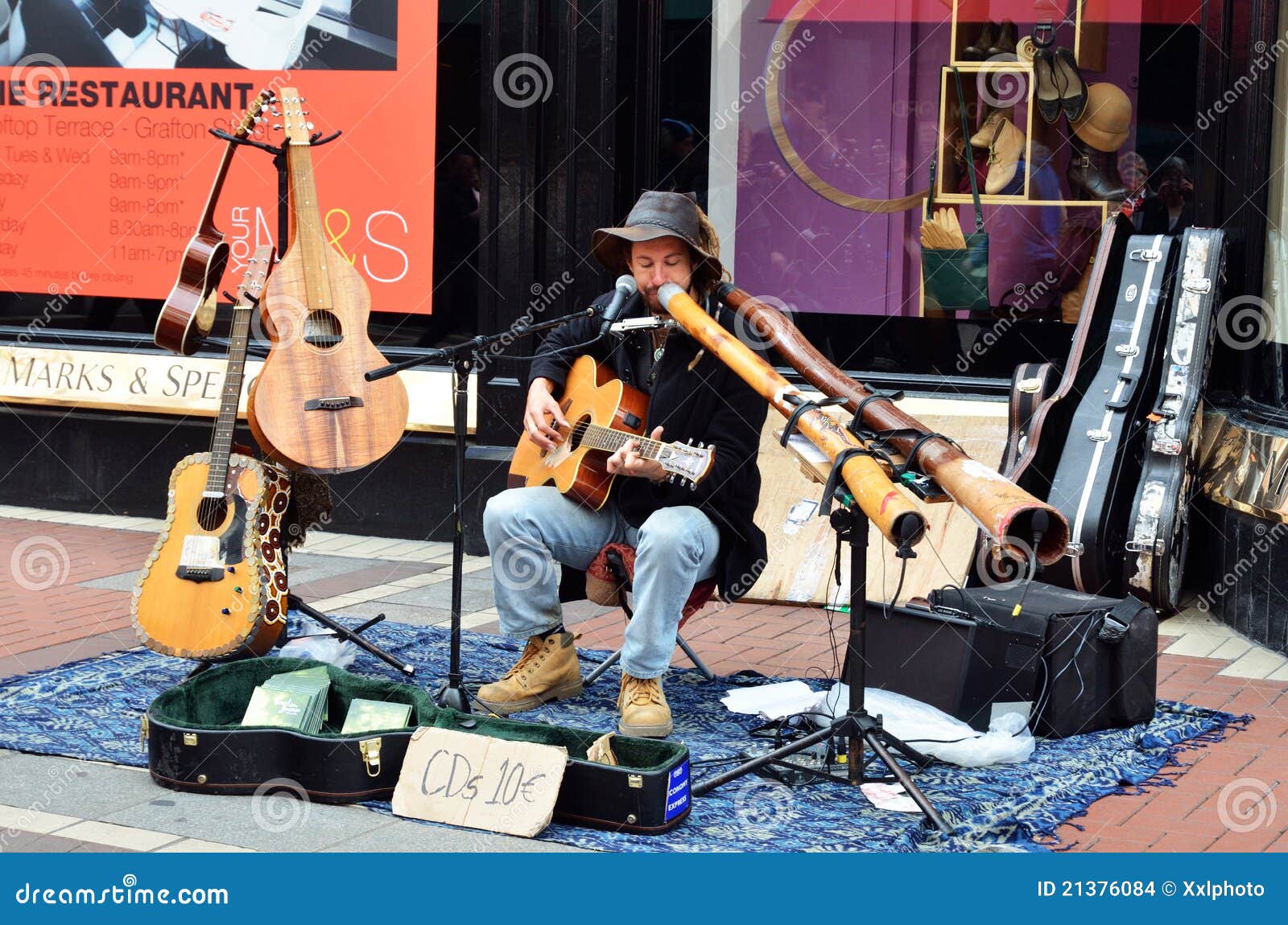 Músico da rua que joga o didgeridoo e a guitarra na rua na cidade