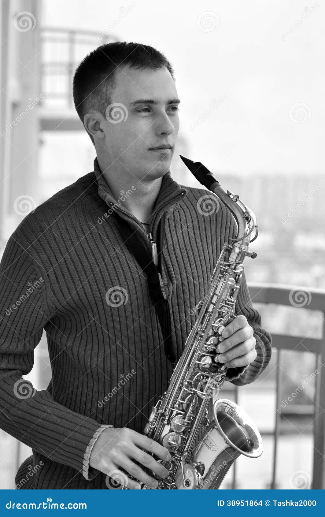 Mężczyzna z saksofonem. Przystojny młody człowiek bawić się na saksofonowy plenerowym