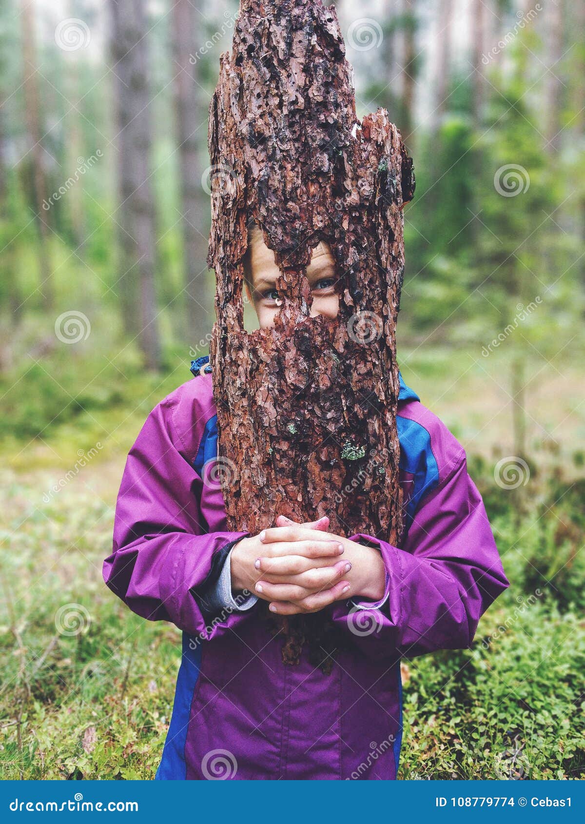 Młoda figlarnie dziewczyna trzyma kawałek drzewna barkentyna jako twarzy maska. Portret trzyma kawałek drzewna barkentyna jako twarzy maska outdoors w lesie śmieszna młoda dziewczyna
