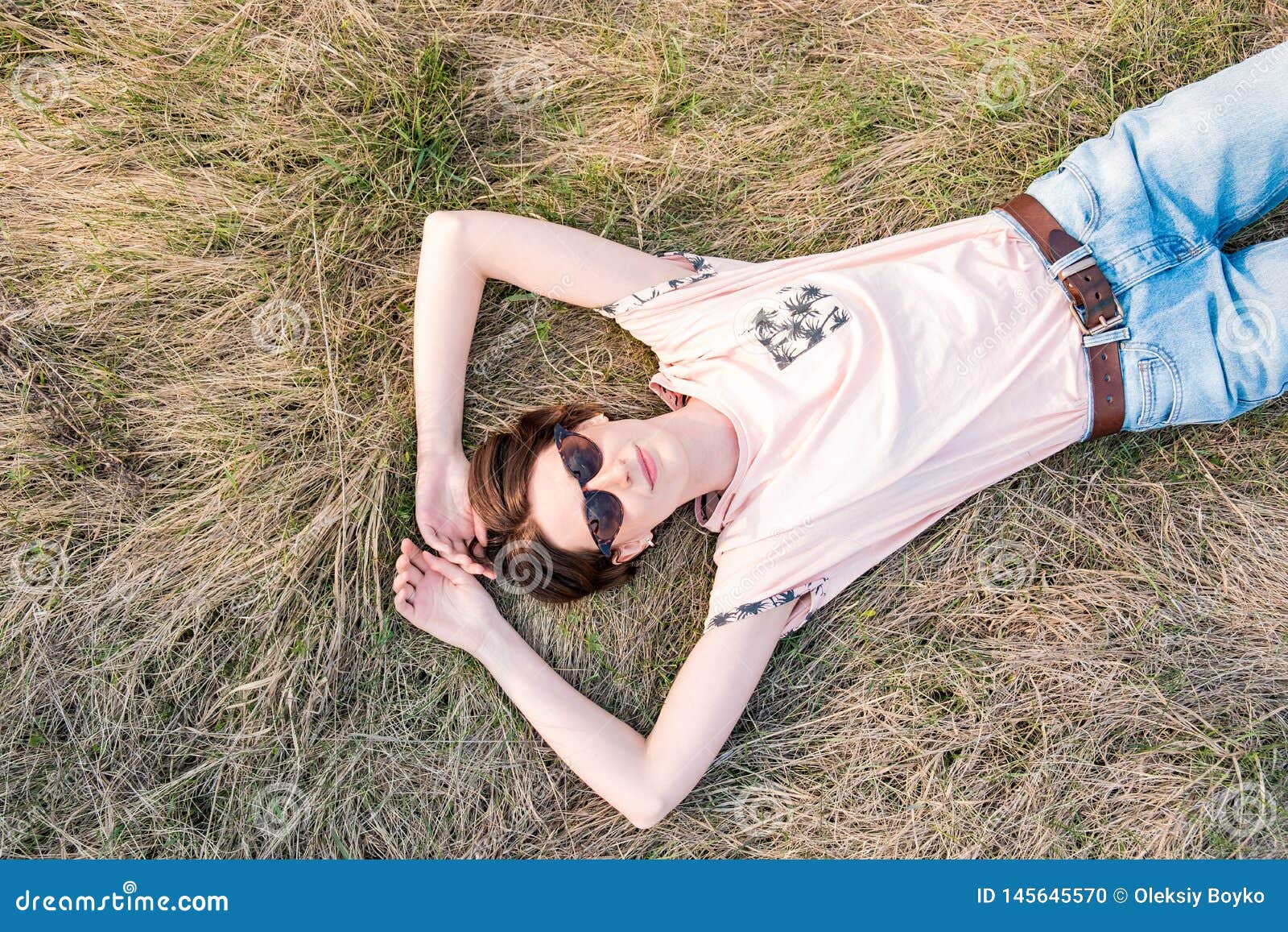 Młoda kobieta na trawie bierze czas doceniać wiosnę. Odgórny widok uśmiechnięta żeńska osoba kłaść w łące lub odpowiada patrzeć niebo