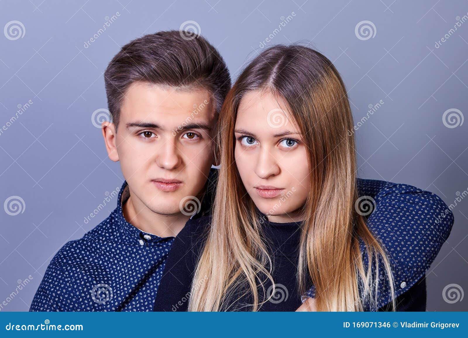 Młody mężczyzna i kobieta patrzą na kamerę. Młodzi mężczyźni i kobiety o kaukaskim wyglądzie, 20 lat, patrzą na kamerę, pozując fotografa, zbliżenie Brat i siostra albo facet z dziewczyną przytulają się do salonu.