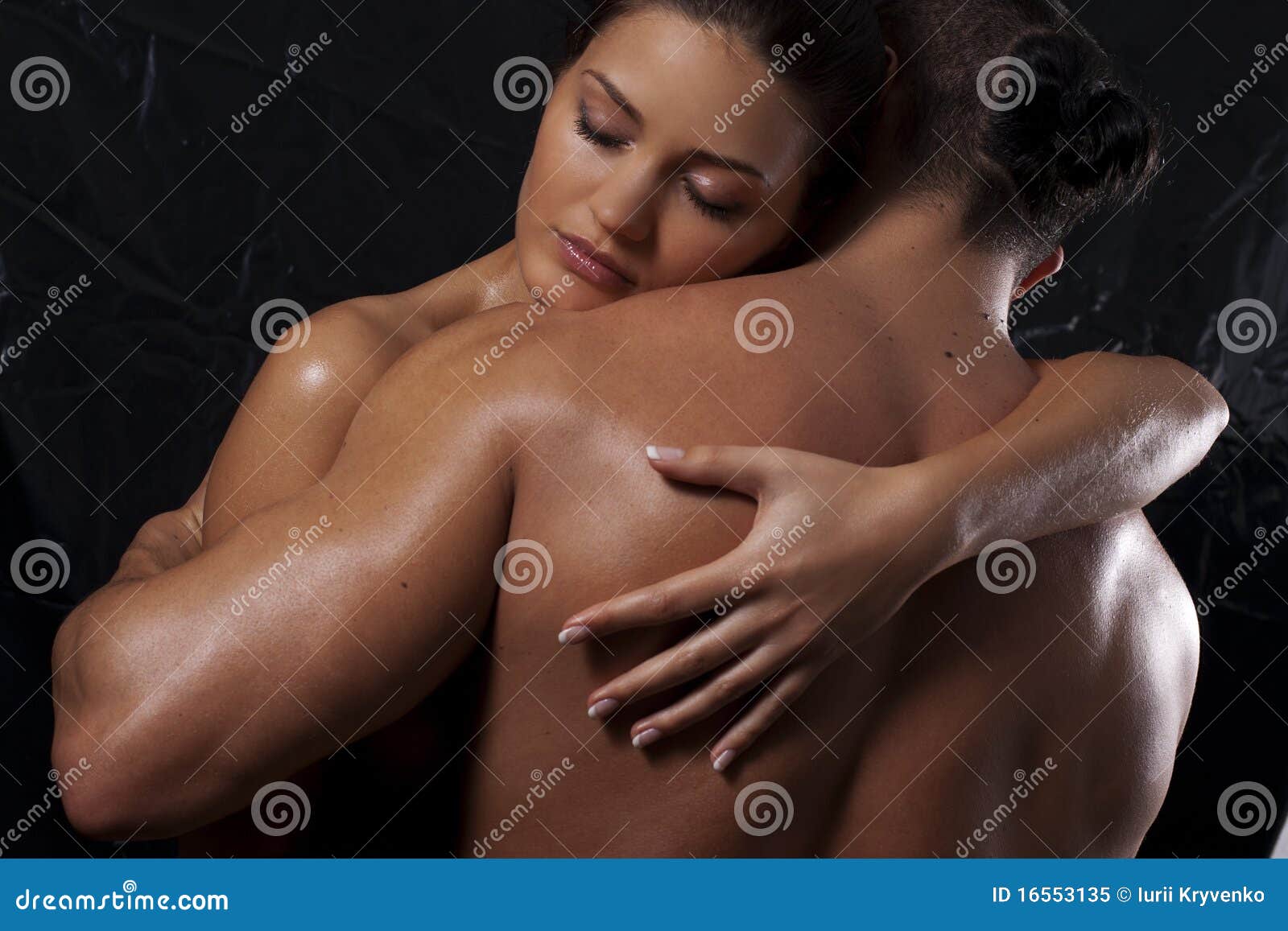 Two nude females lying on bed side by side, hugging and touching stock photo