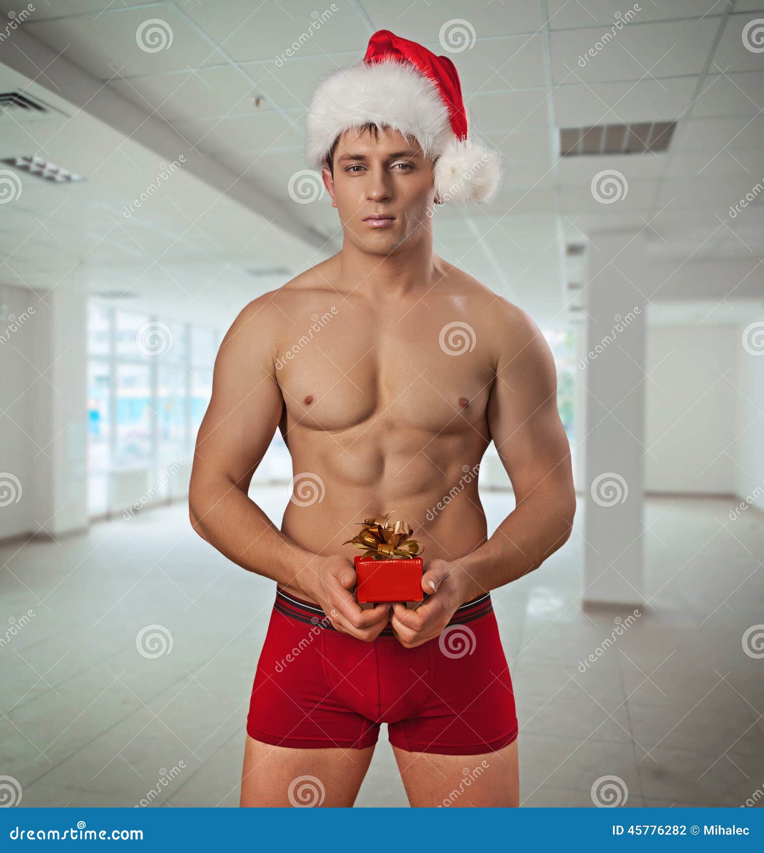 Premium Photo  Shirtless macho man in santa hat holding gifts