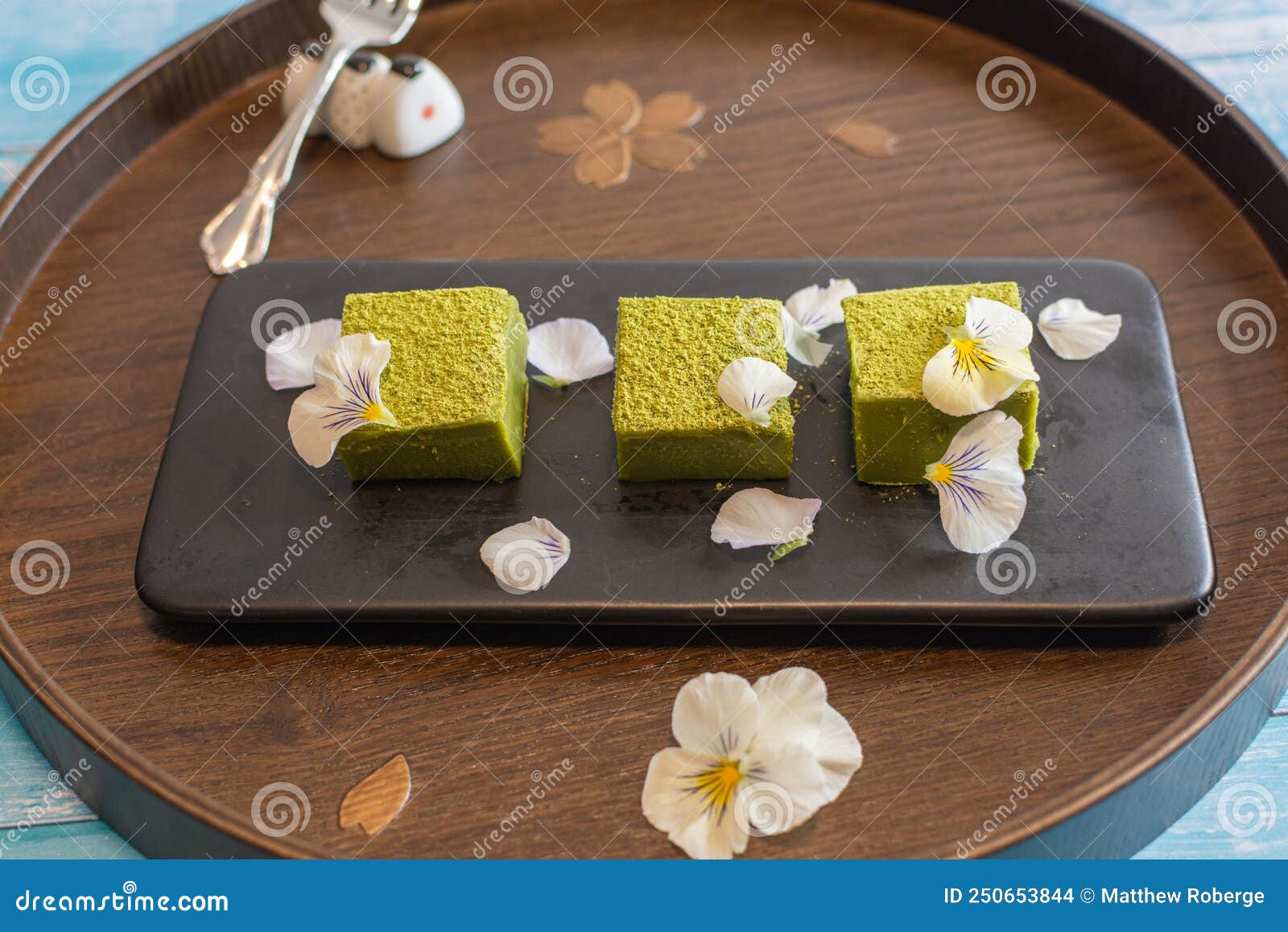 nama matcha chocolate with edible flowers on a traditional wooden tray