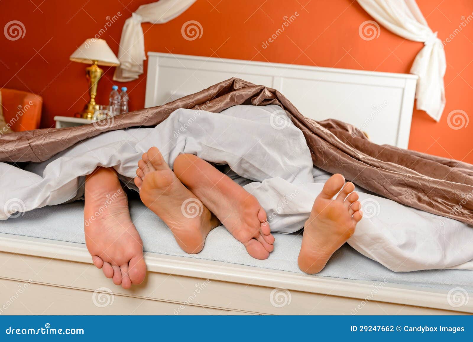 napping couple barefoot lying under covers bed
