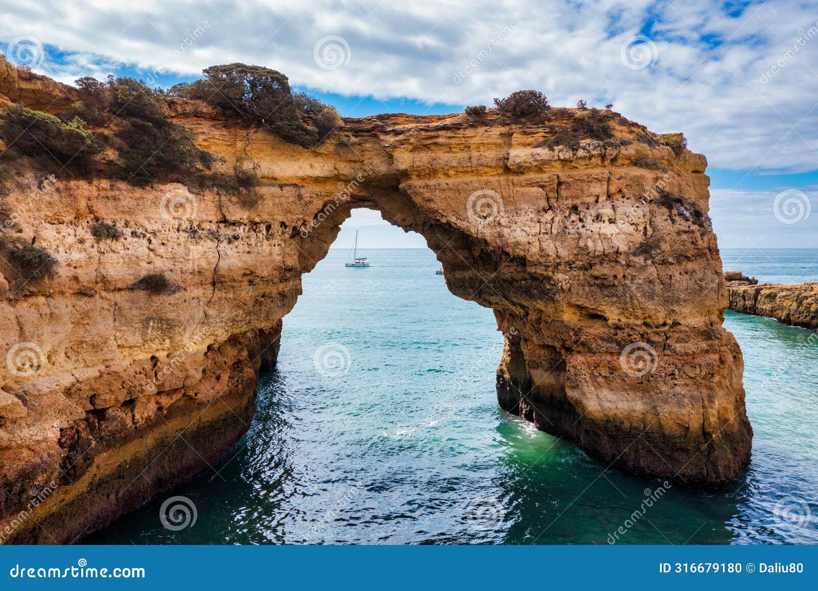 natural arch above ocean, arco de albandeira, algarve, portugal. stone arch at praia de albandeira, lagoa, algarve, portugal. view