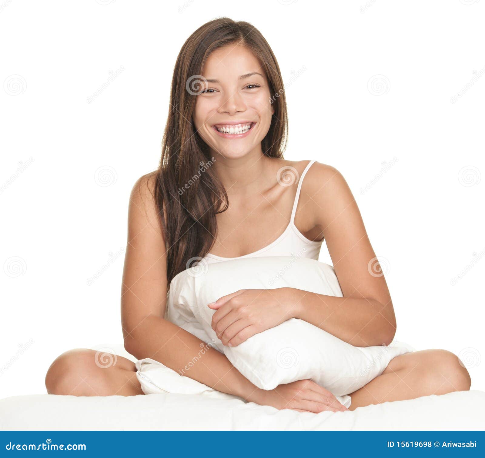 Woman with vitiligo holding pillow between legs on bed in front of