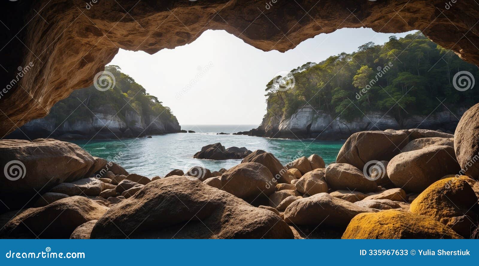 natural forest scenery viewed from a shadowy coastal cave encircled by worn rock formations.