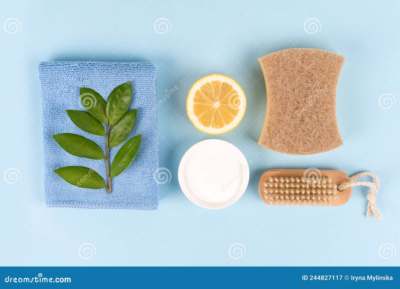 natural household cleaners - baking soda, lemon, citric acid, bamboo brush, natural sponge on blue background with copy space