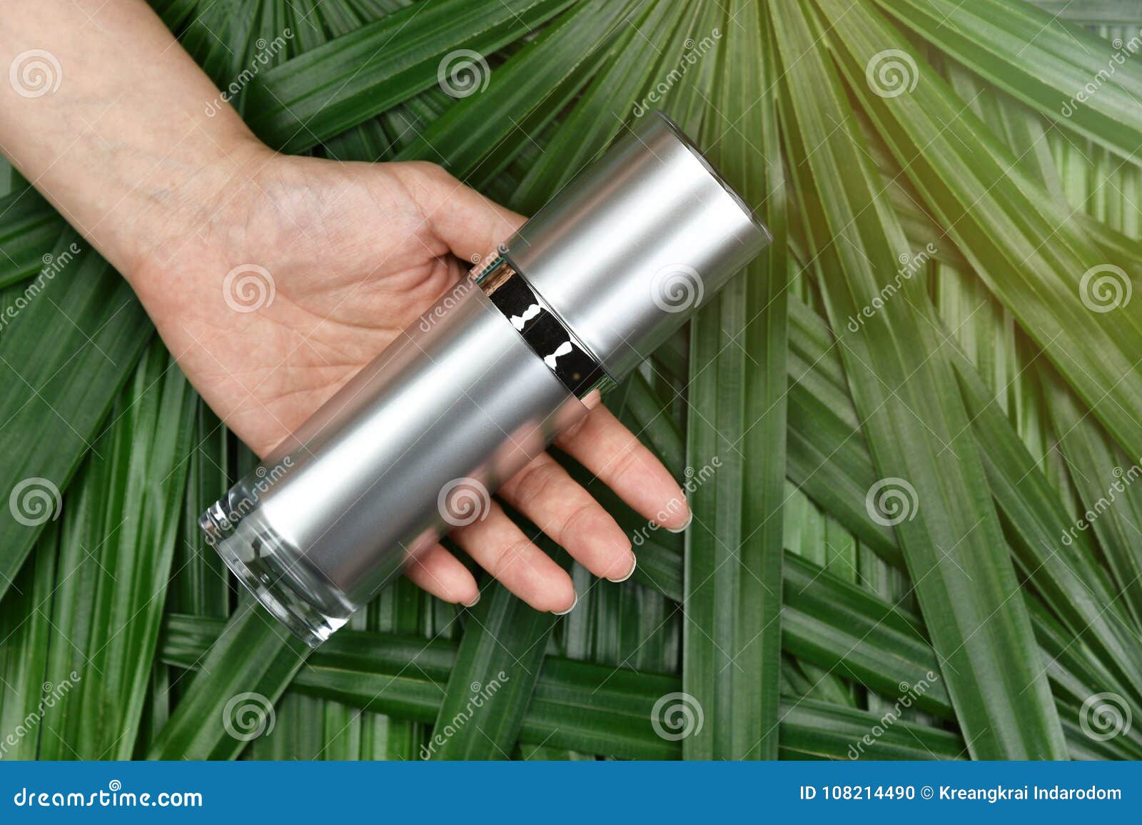 natural skincare beauty product concept, cosmetic bottle containers in hand on green herbal leaves background.