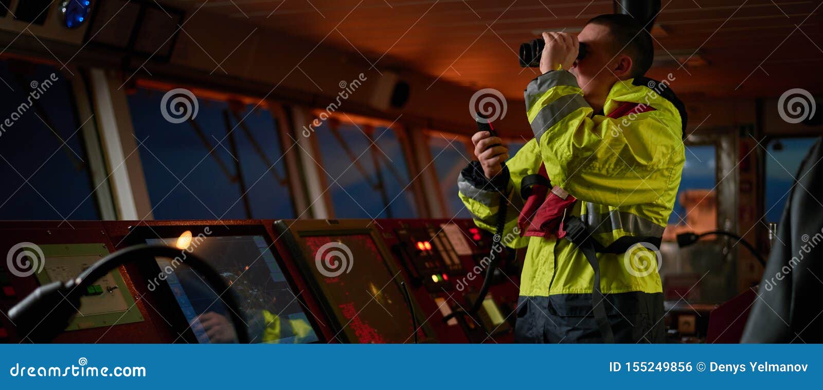 navigator. pilot, captain as part of ship crew performing daily duties with vhf radio, binoculars on board of modern ship with