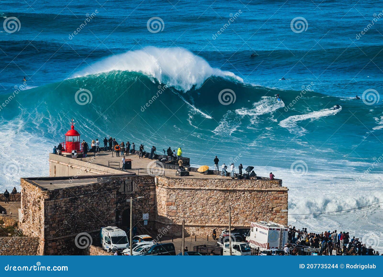 nazare, portugal, surfer riding giant wave in front of nazare lighthouse