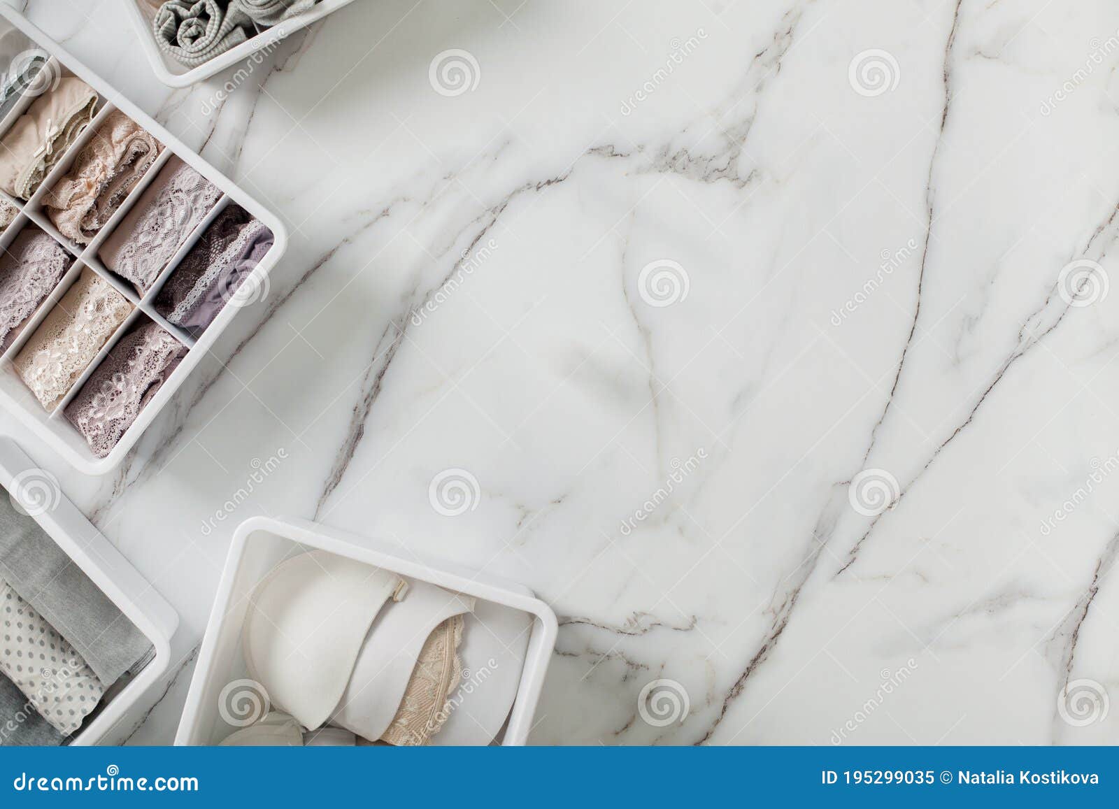 neatly and tidy folded lingeries in organizer drawer divider on white marble background.