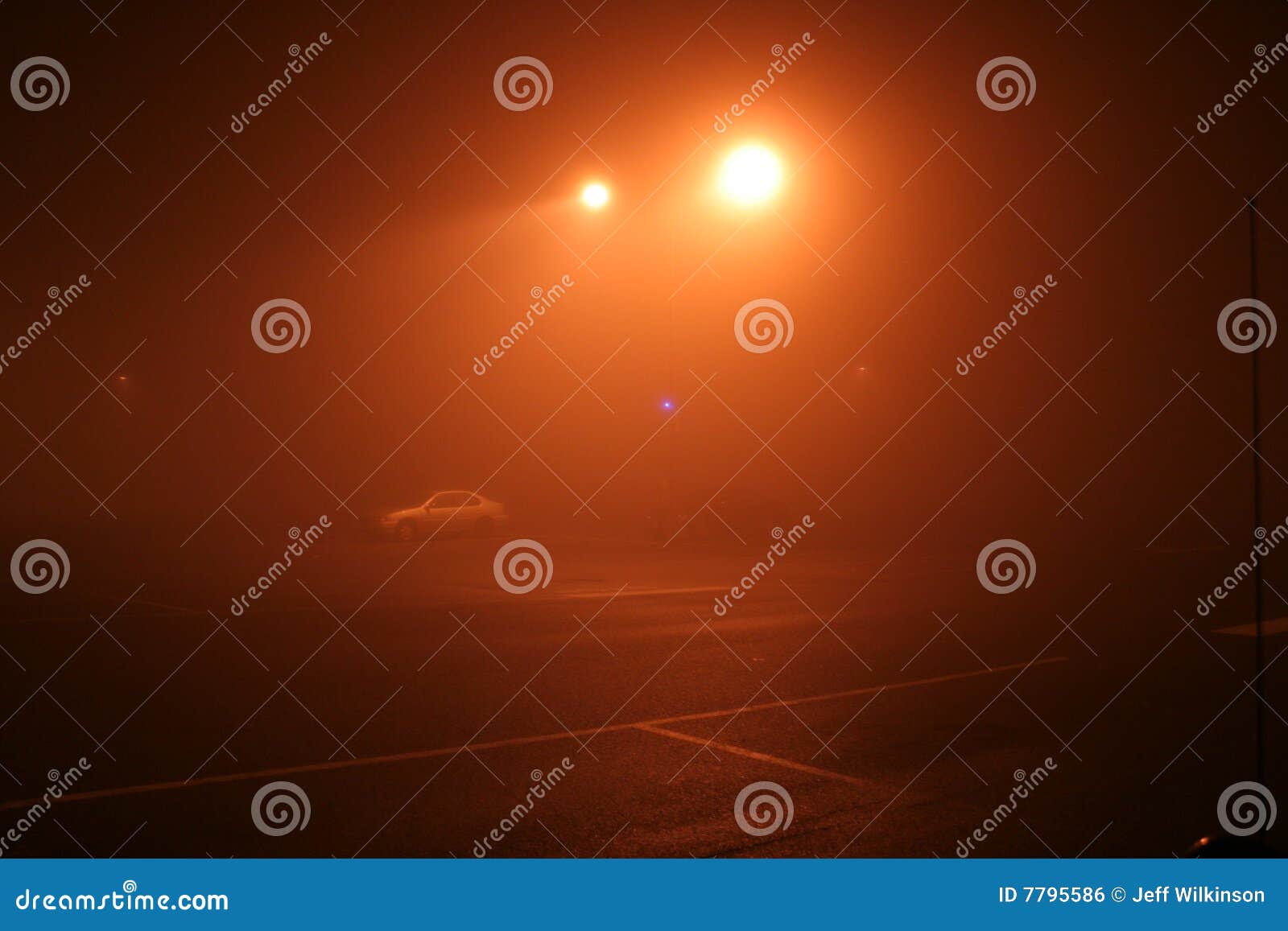 Nebeliger NachtzeitParkplatz. Goldene Lichtstrahlen glänzen durch dichten Nebel in einem dunklen leeren NachtzeitParkplatz. Einige Autos können sehr schwach durch das fogMight gesehen werden sind nützlich für die Themen der Gefahr und an der Nacht und nicht in der Lage sein zu sehen, an usw. alleine gehen. WARNING: etwas Geräusche, zwar relativ niedrig für diesen Typen des Nachtzeitschusses, sollten ein nützlicher Schuß sein