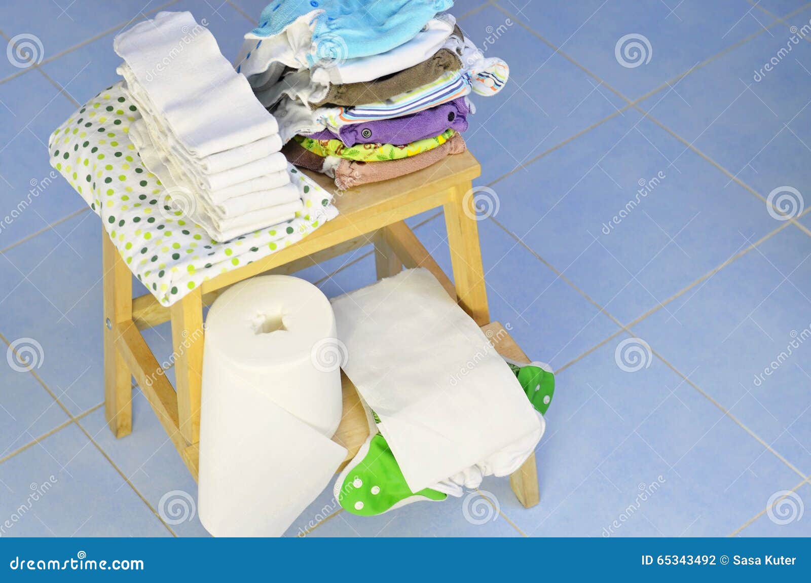 needs for babies: cloth diapers, nappy liners, changing pad are prepared on wooden stool.