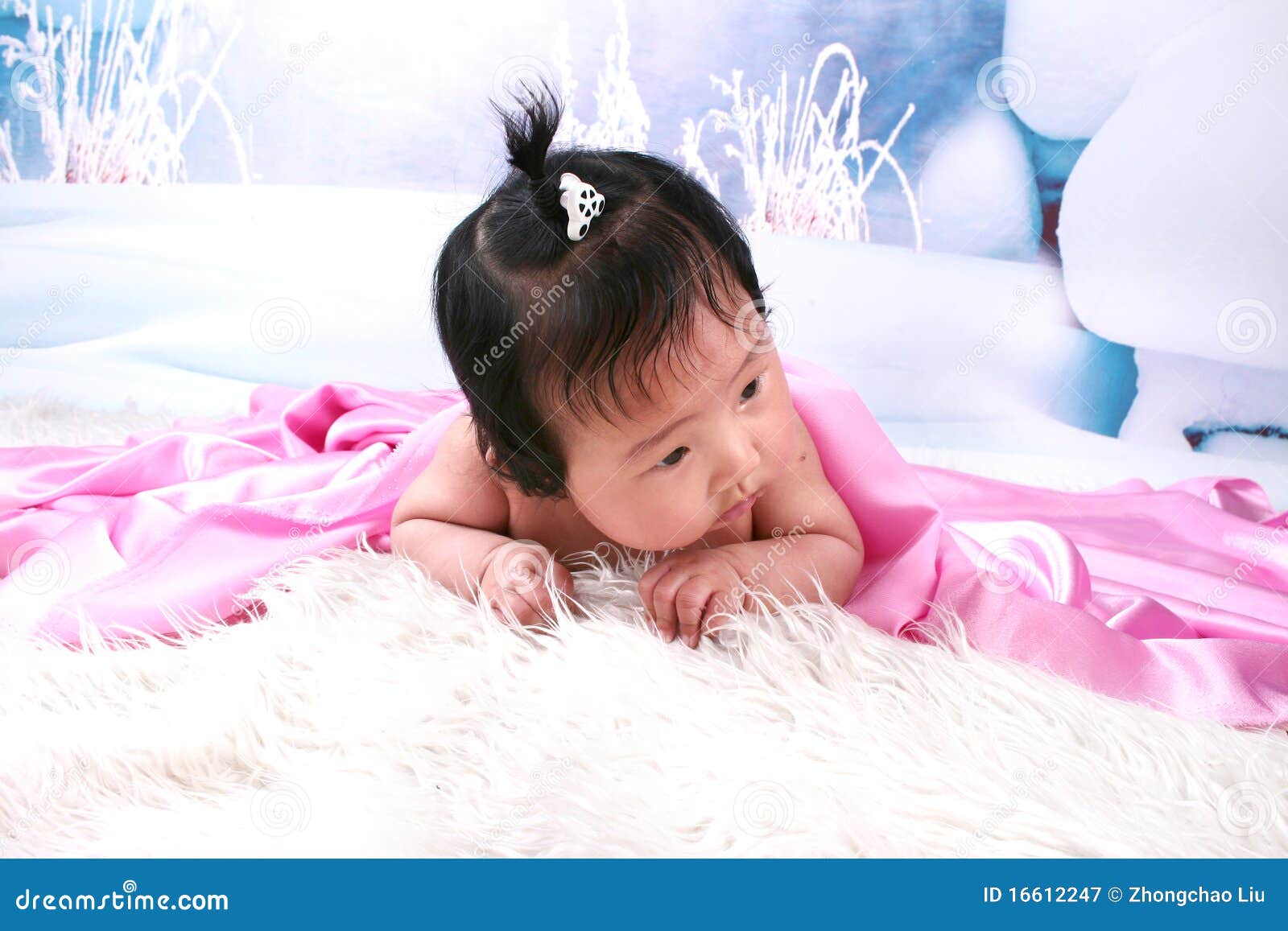 Neonata sveglia sotto la coperta. Bella neonata di Chineae con la piccola treccia che osserva fuori da sotto la coperta