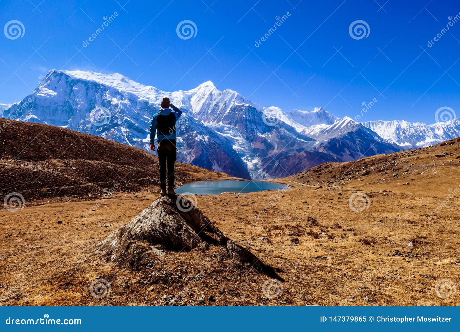 nepal - man standing on a rock in the nearby of the ice lake, annpurna circuit trek in himalayas.