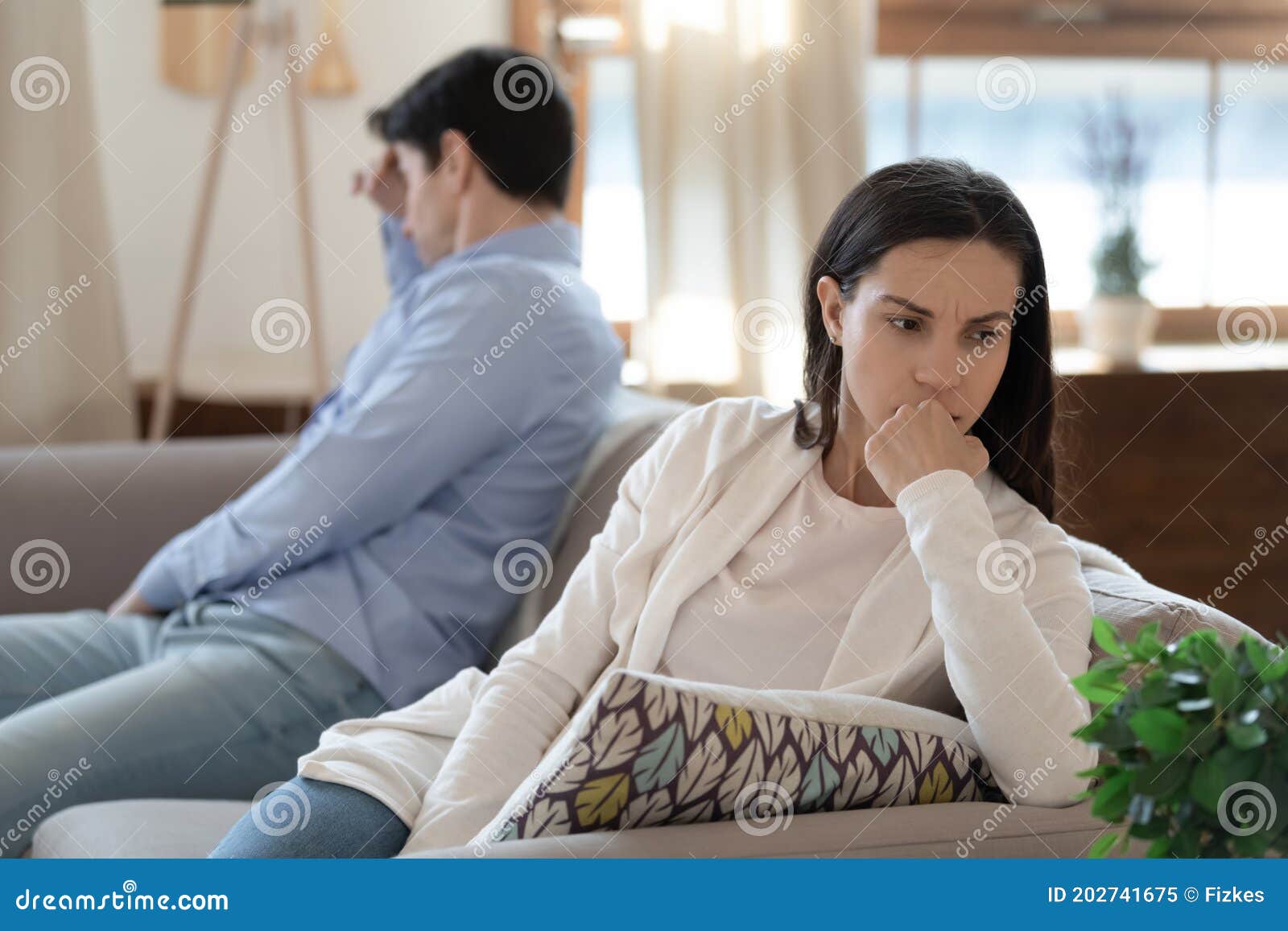 nervous young couple sitting on sofa keeping silence after argument