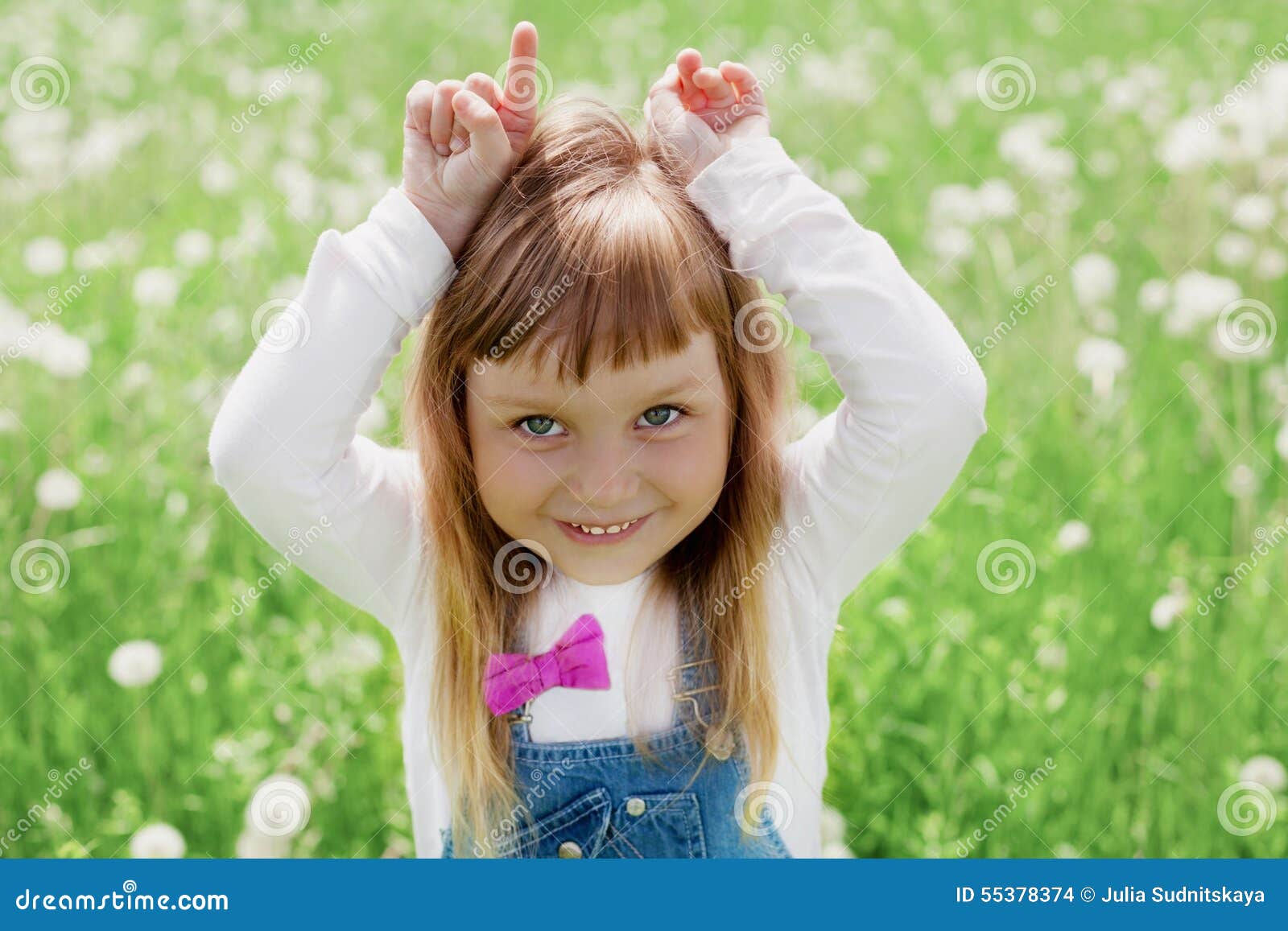 Nettes kleines Mädchen, das mit ihren Händen darstellen eine Ziege auf der grünen Wiese im Freien, glückliches Kindheitskonzept l. Nettes kleines Mädchen, das mit ihren Händen darstellen eine Ziege auf der grünen Wiese im Freien, glückliches Kindheitskonzept, Kind hat Spaß, Weinlese getont lacht und spielt