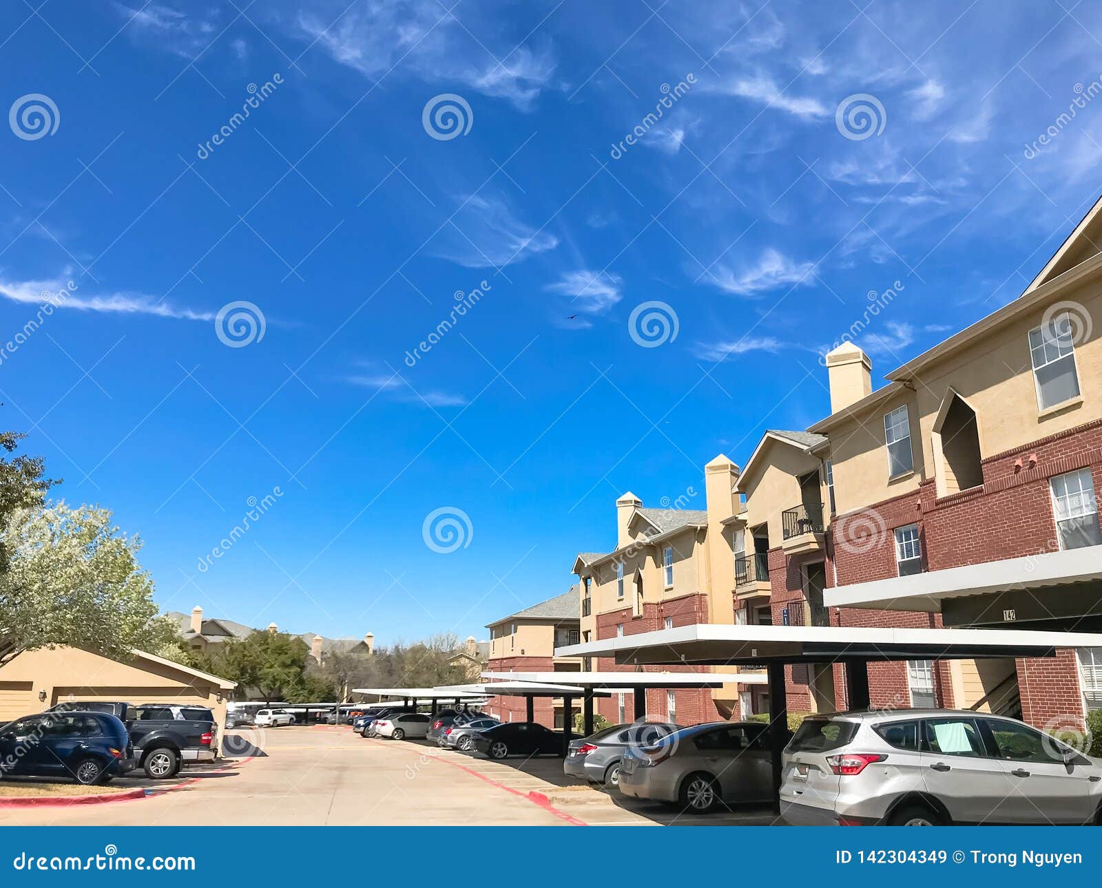 New Apartment Complex with Covered Parking Under Sunny Cloud Sky in