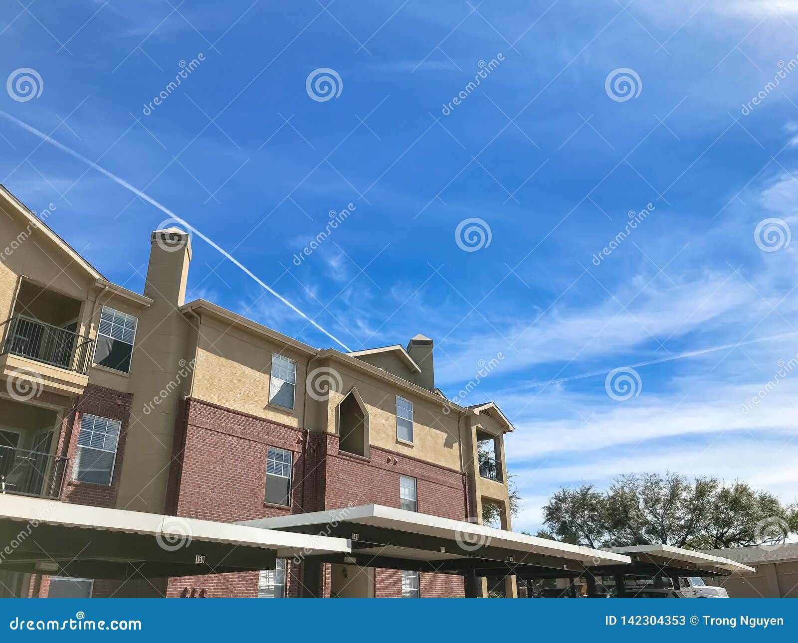New Apartment Complex with Covered Parking Under Sunny Cloud Sky in