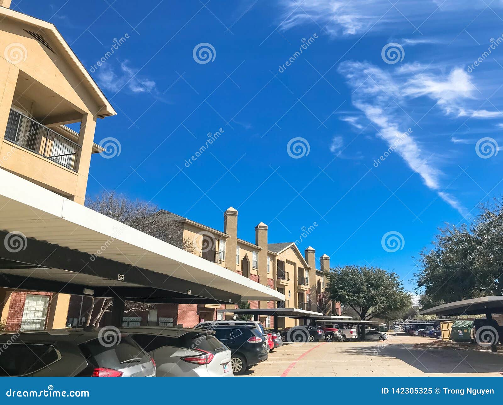 New Apartment Complex with Covered Parking Under Sunny Cloud Sky in