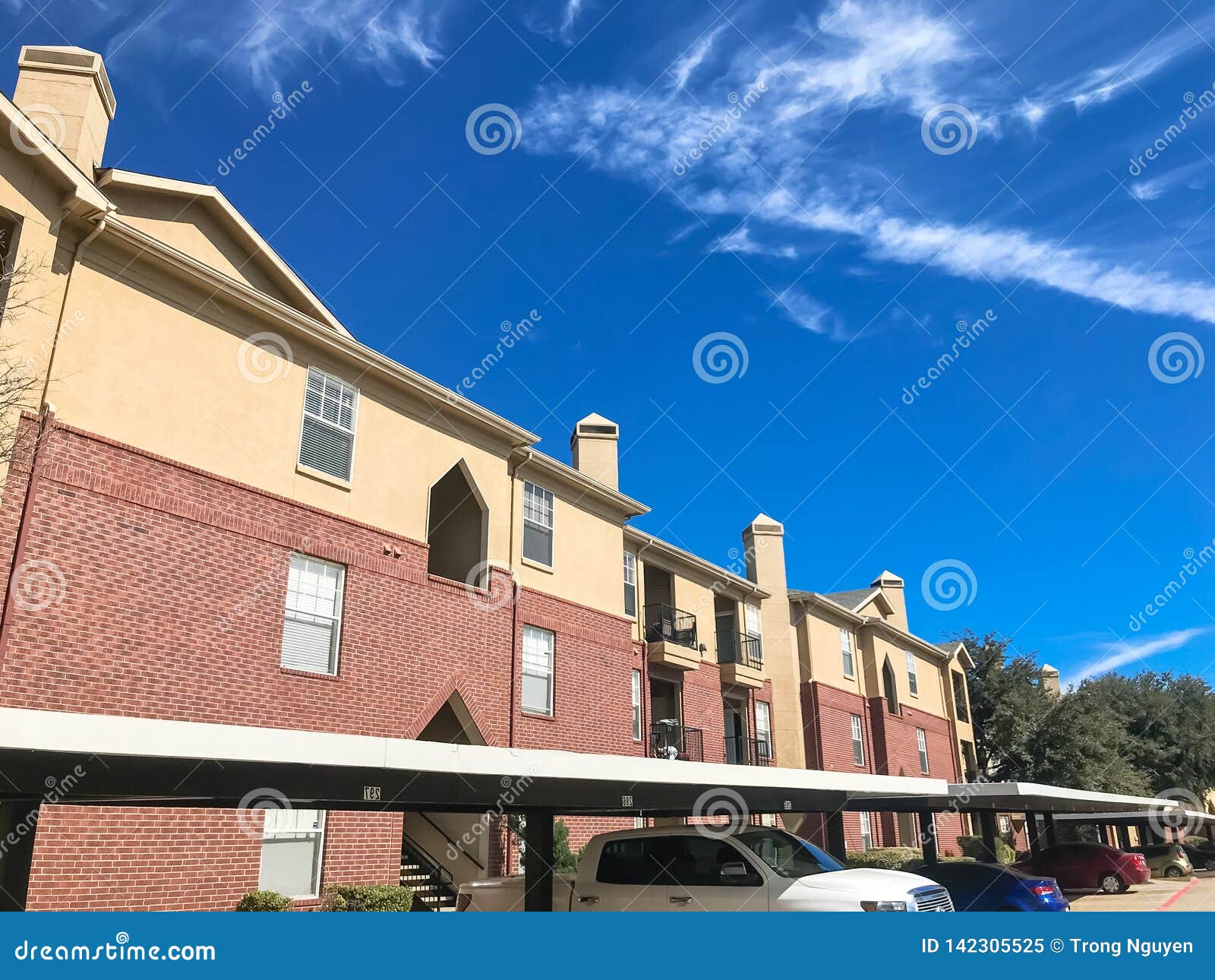 New Apartment Complex with Covered Parking Under Sunny Cloud Sky in